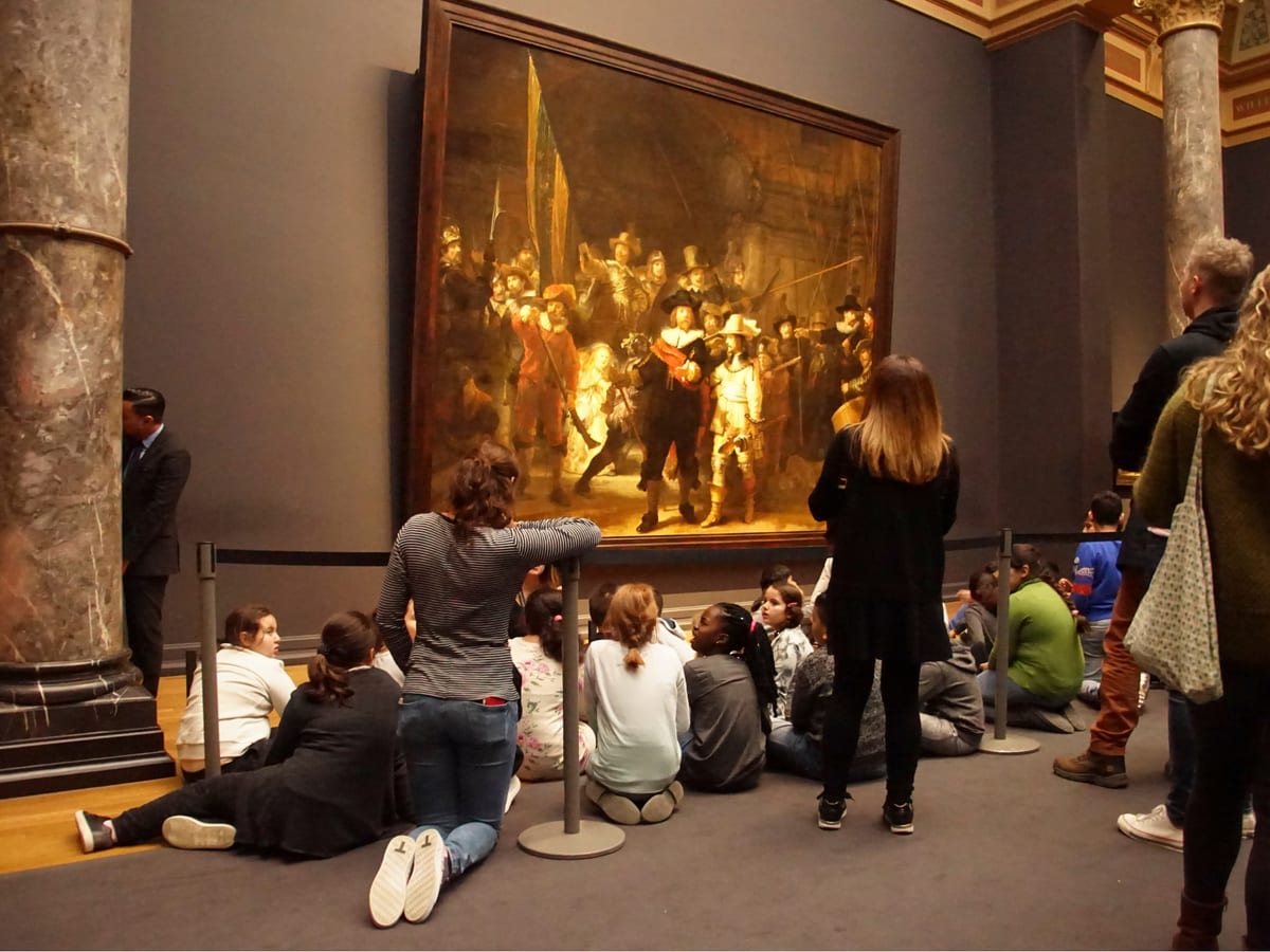 Des élèves assis par terre devant La Ronde de nuit de Rembrandt